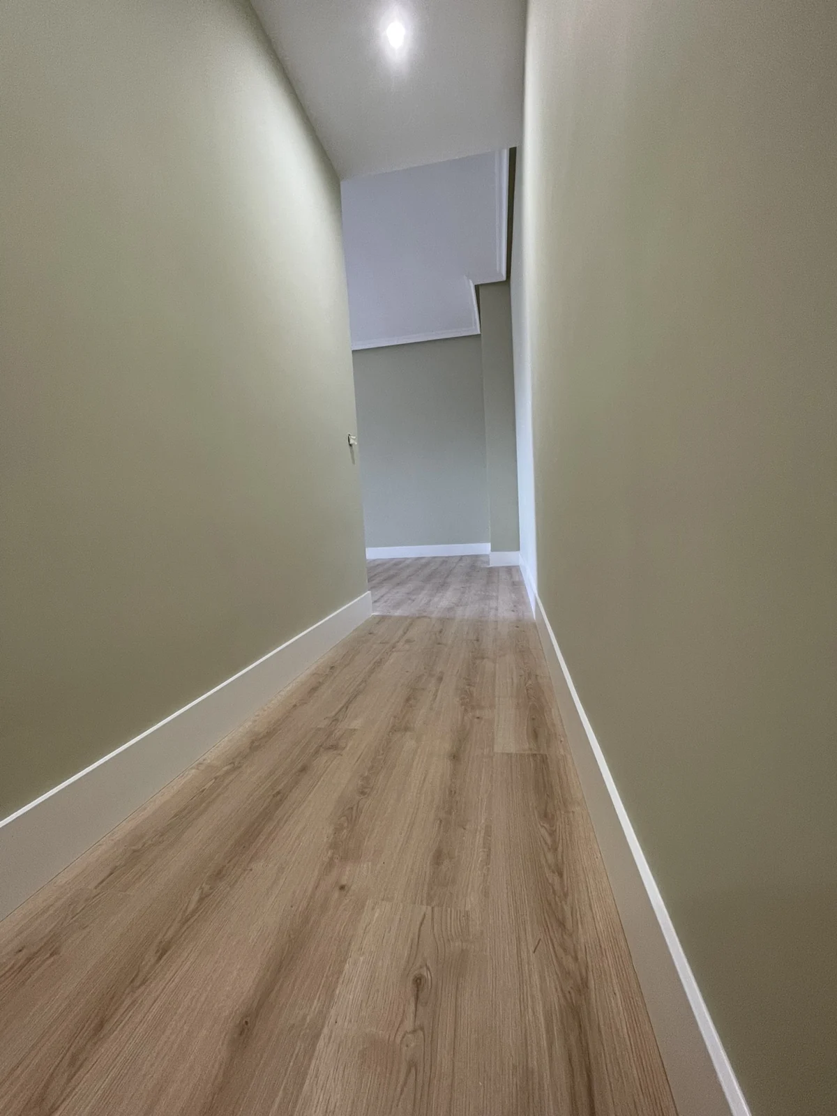 Pasillo con el suelo laminado color roble y el rodapié blanco instalado.